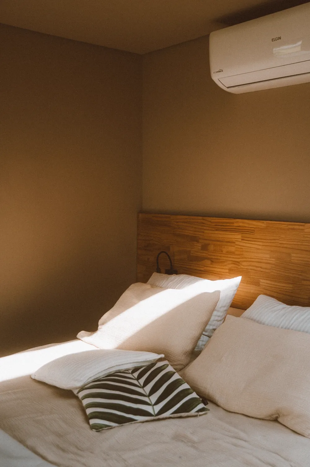 Cama arrumada com almofadas e luz de fim de tarde
