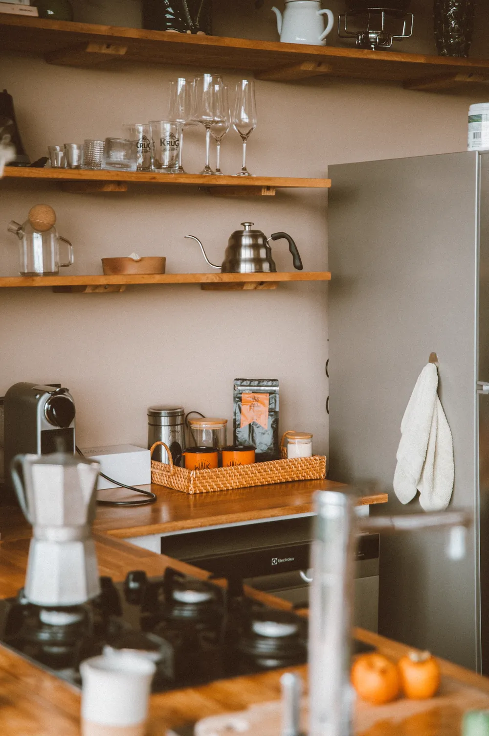 Cozinha com prateleiras de madeira, cafeteira e taças